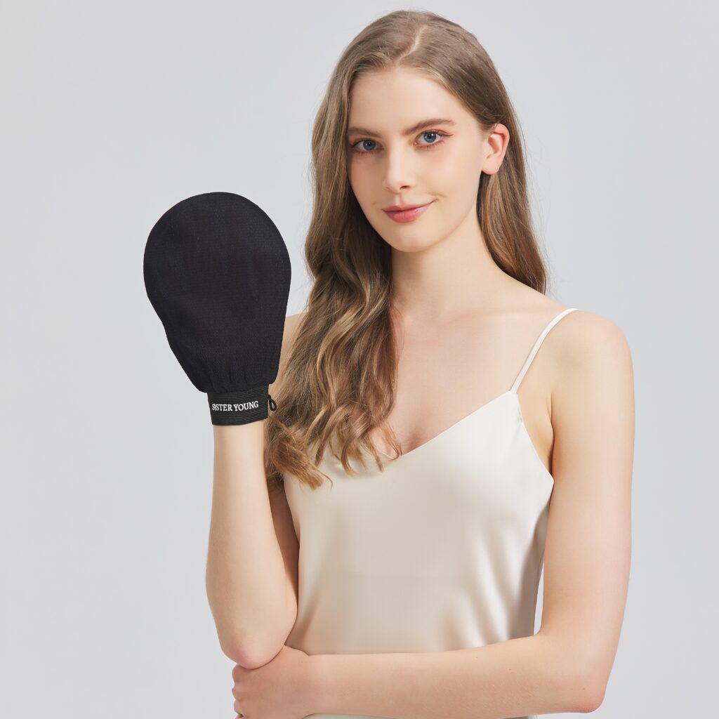 Modelka prezentuje czarną rękawicę do peelingu ciała NOVA BLACK założoną na dłoń.