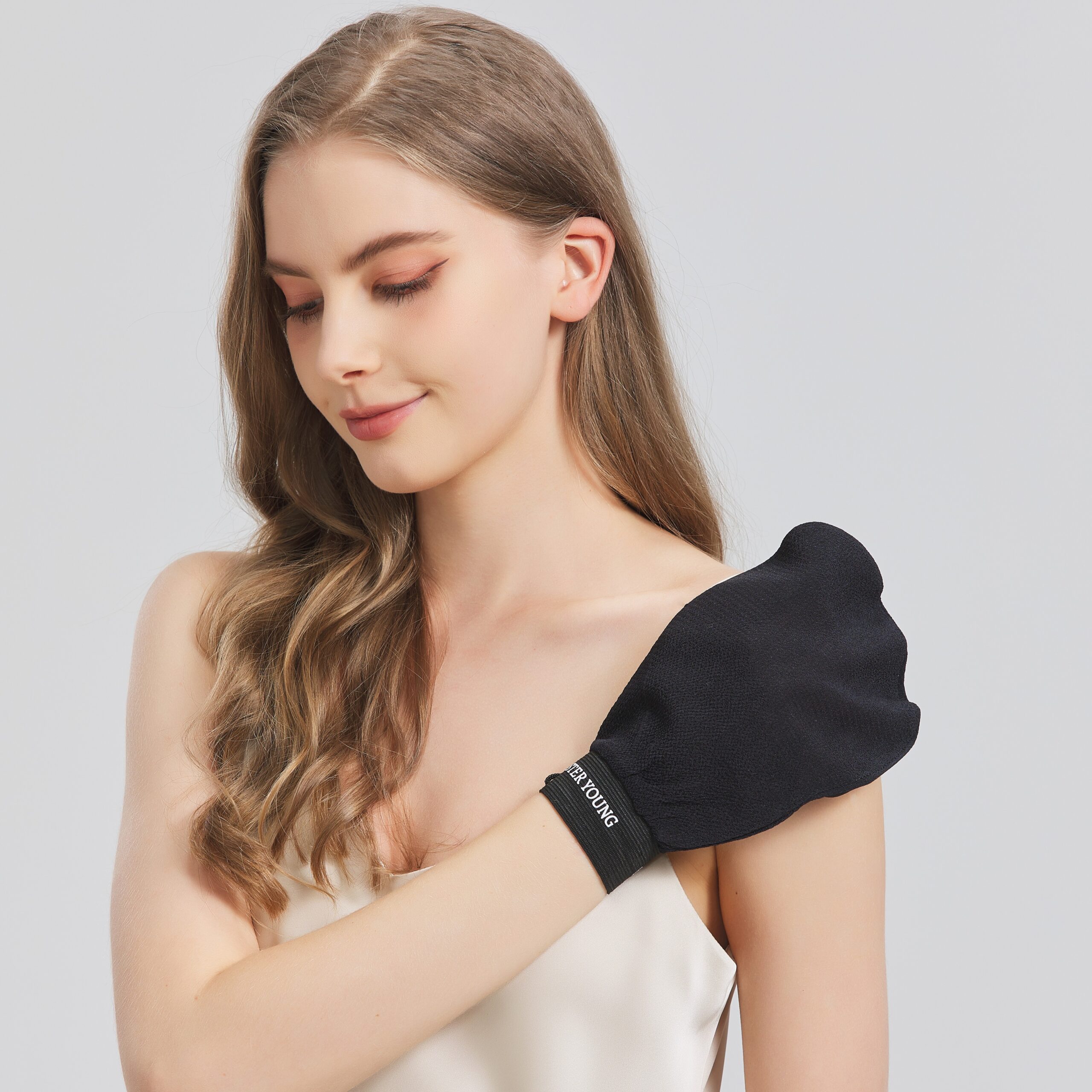 Modelka przykłada czarną rękawicę do peelingu NOVA BLACK do ramienia.