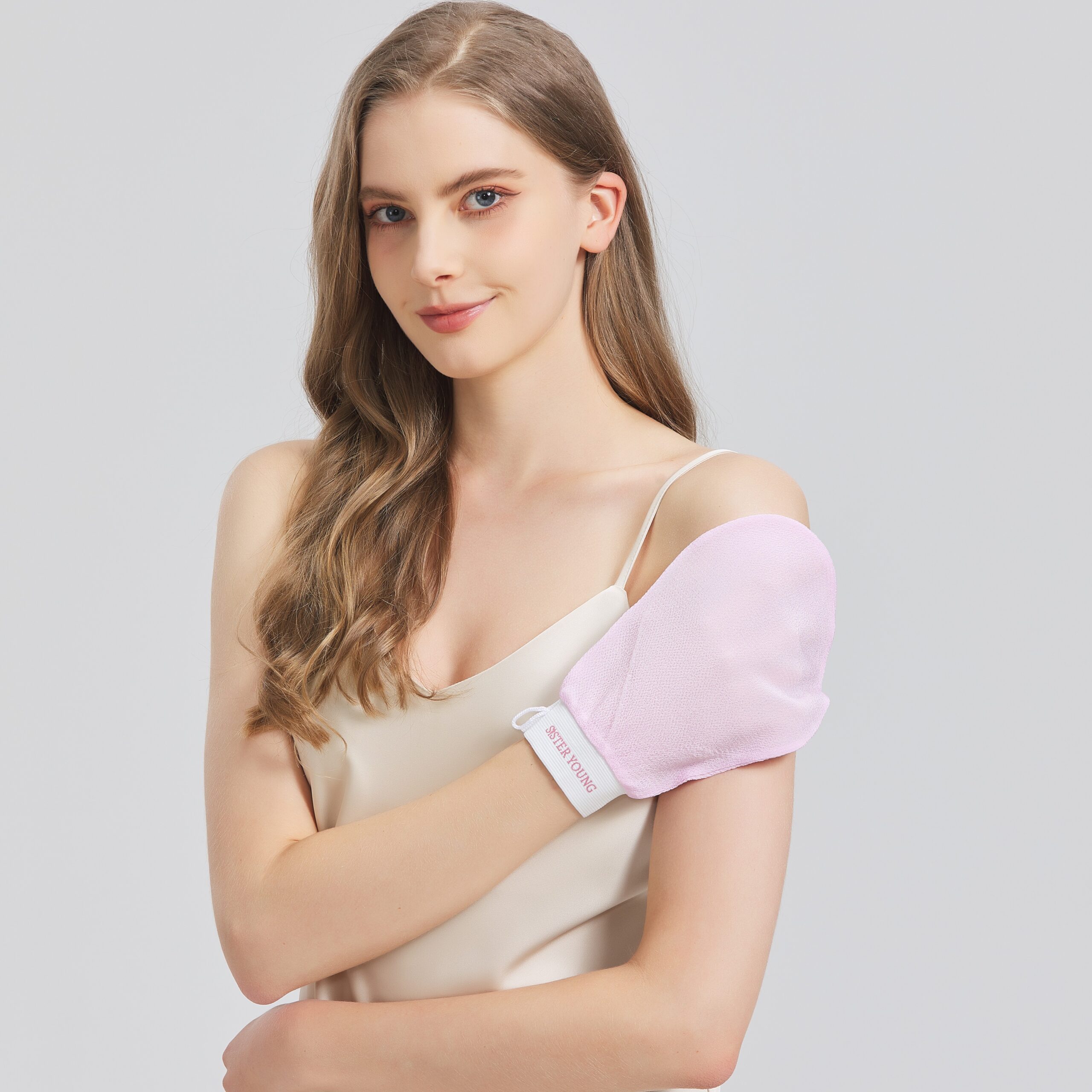 Modelka przykłada różową rękawicę do peelingu NOVA PINK do ramienia.