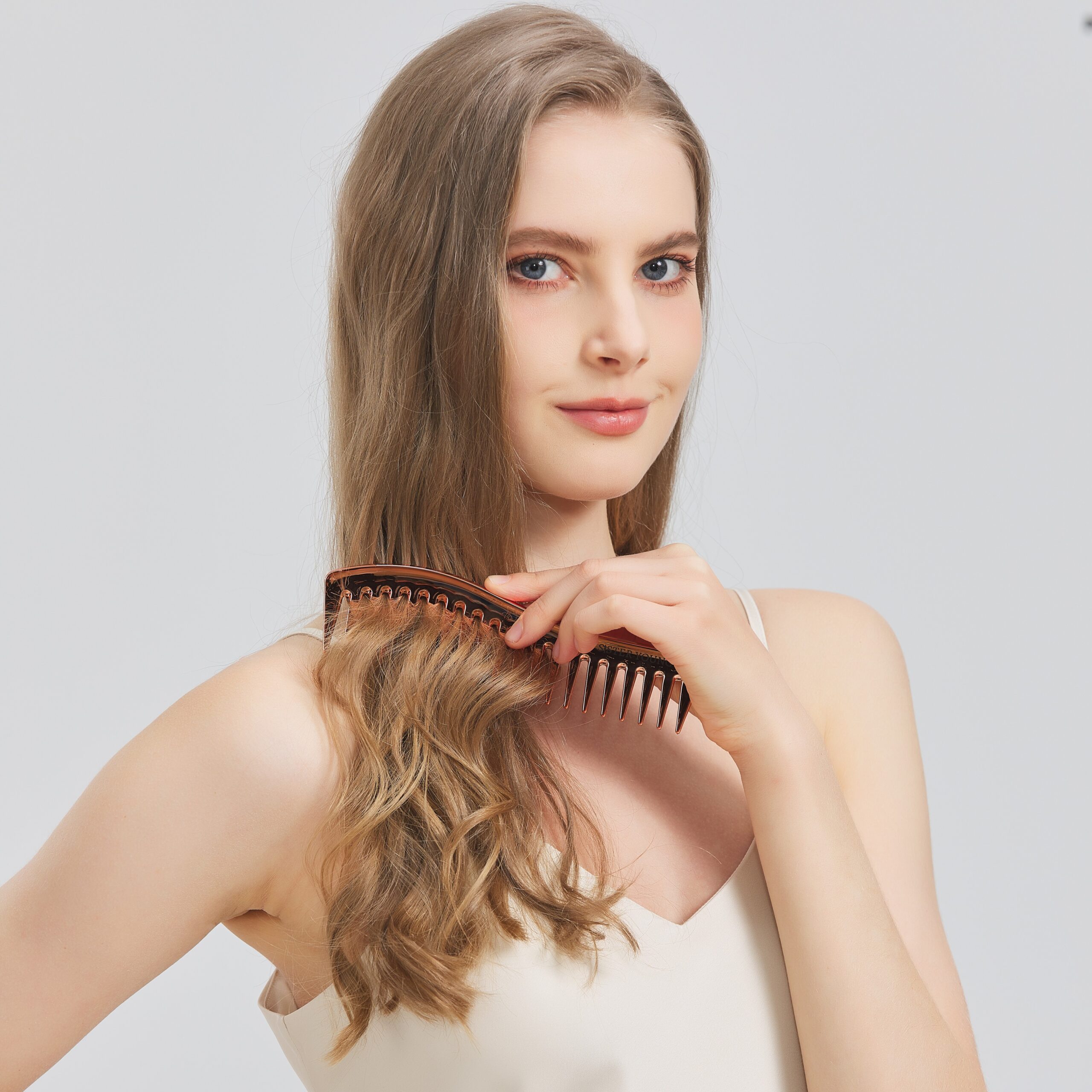 Modelka rozczesuje pasmo włosów grzebieniem Zuri Rose Gold