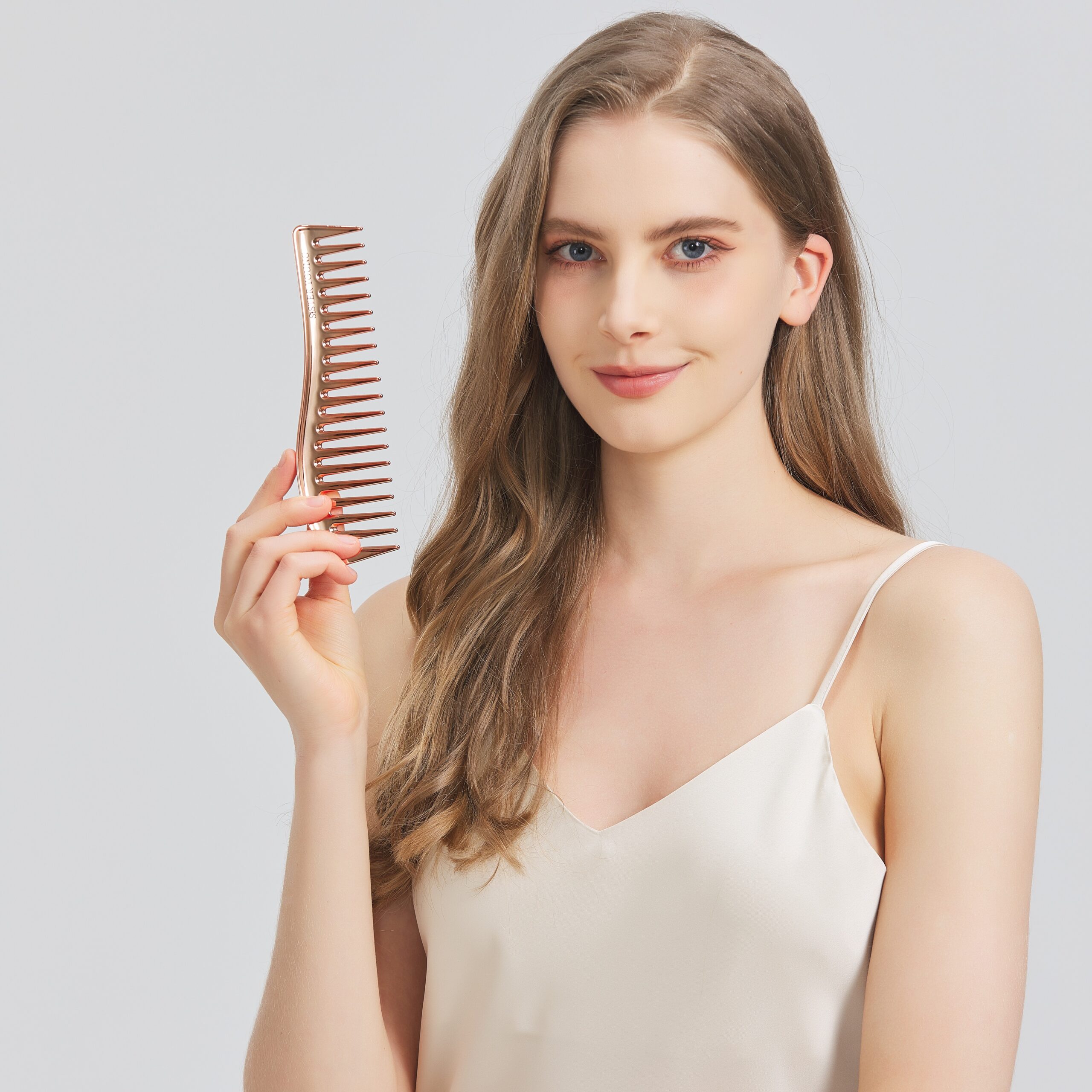 Modelka trzyma grzebień Zuri Rose Gold przy twarzy — ujęcie z półprofilu
