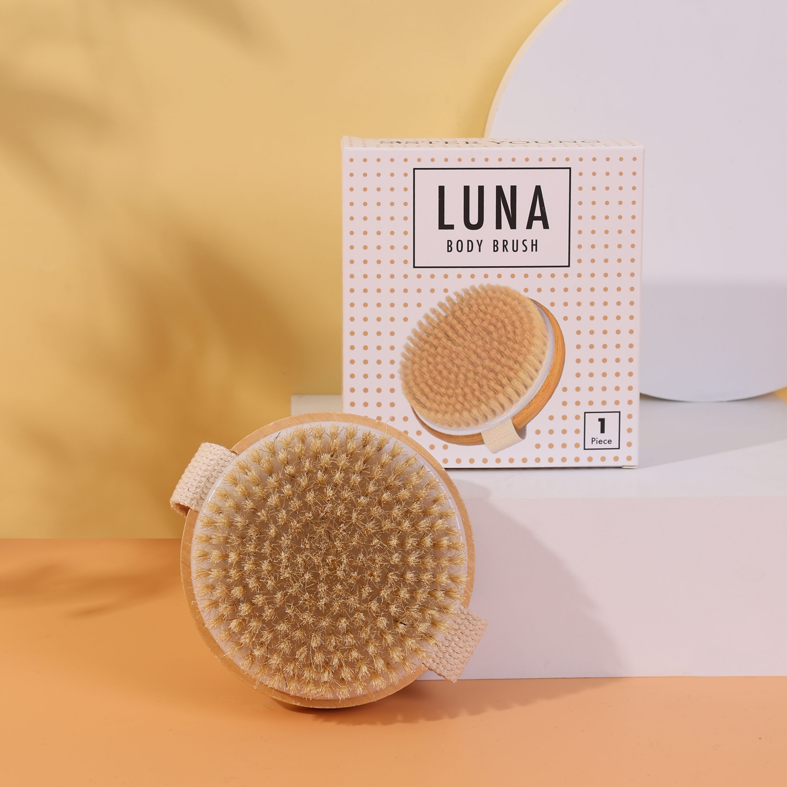 Szczotka do masażu ciała LUNA i jej opakowanie w jasnej, minimalistycznej aranżacji.