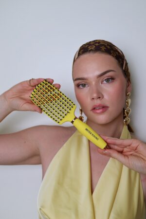 Kobieta prezentująca żółtą szczotkę OVIA Lemon Sister Young w dłoni.