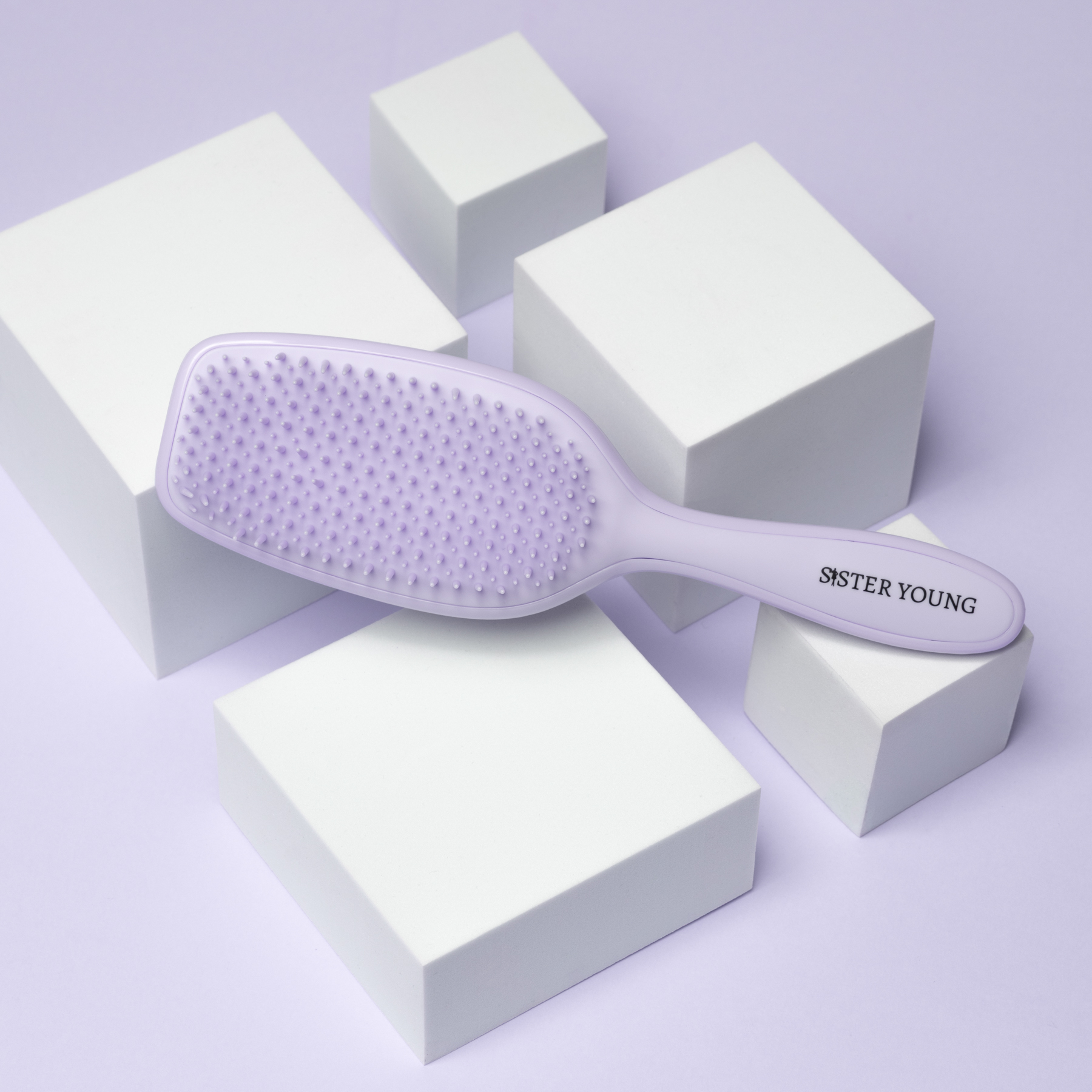 Szczotka Sister Young AYLA Lilac leżąca poziomo na białych kostkach, ząbkami do góry.