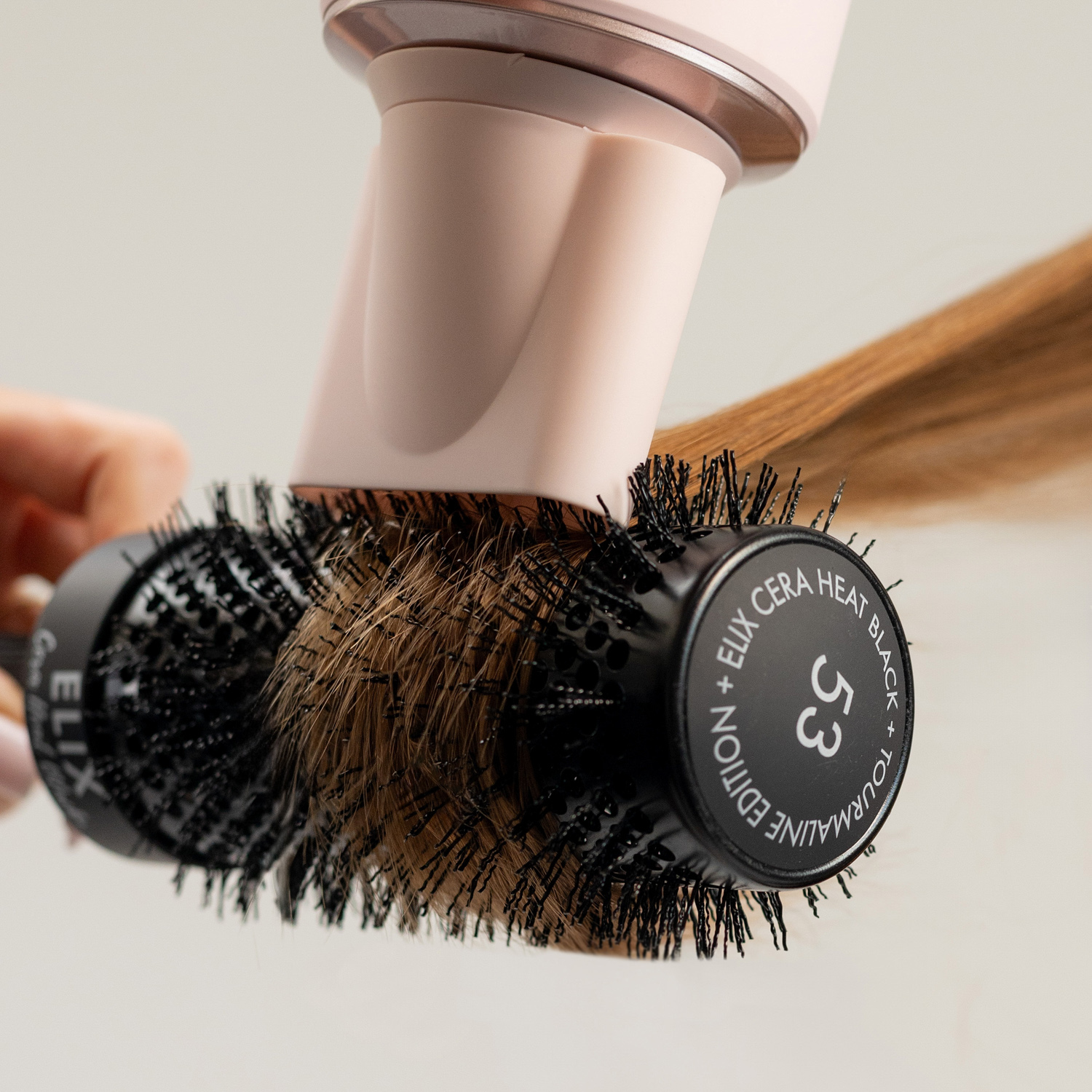 Pasmo włosów modelki nawinięte na czarną okrągłą szczotkę Sister Young ELIX CERA HEAT BLACK+.