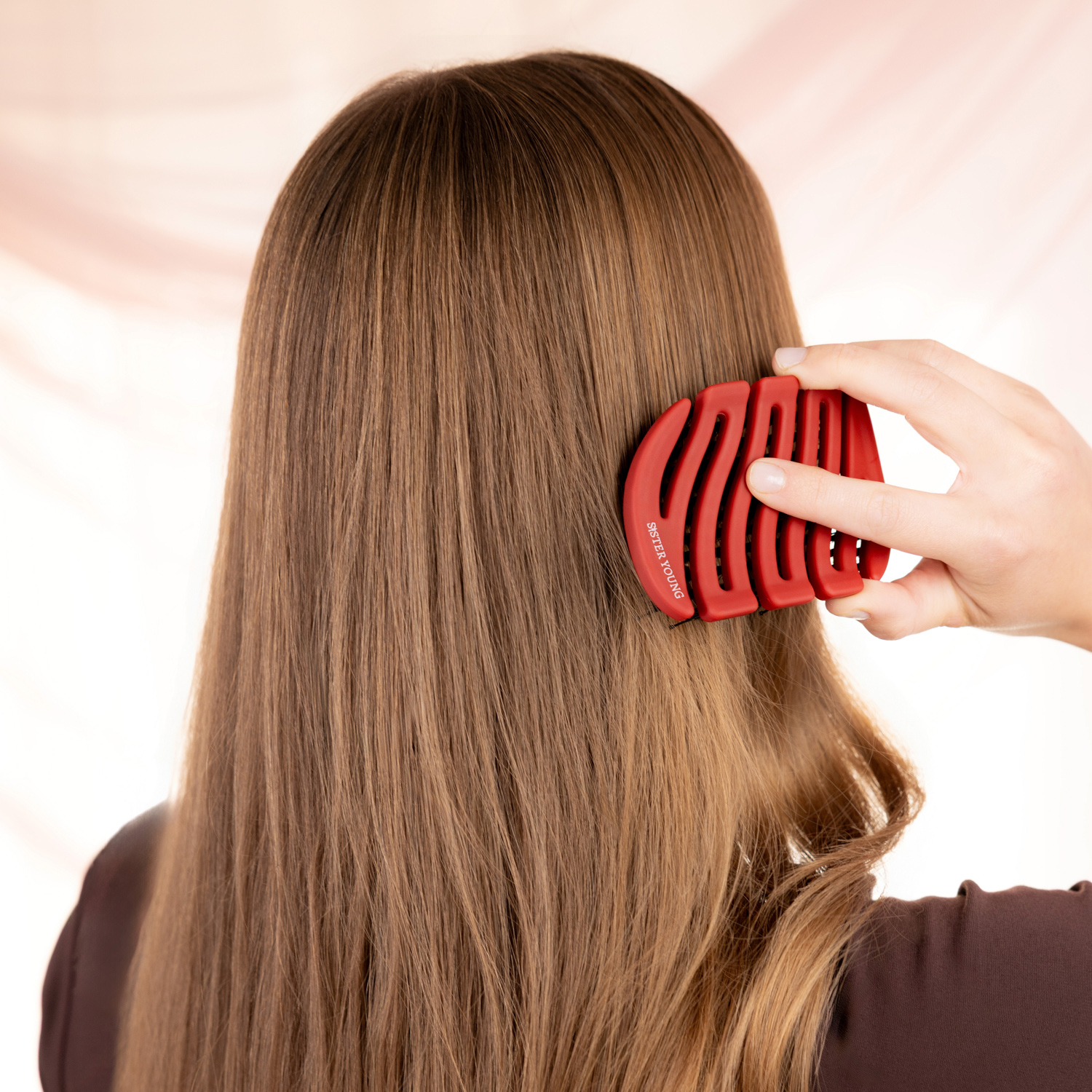 Modelka widziana od tyłu, czesząca długie włosy czerwoną szczotką Sister Young MILA Cherry Red.