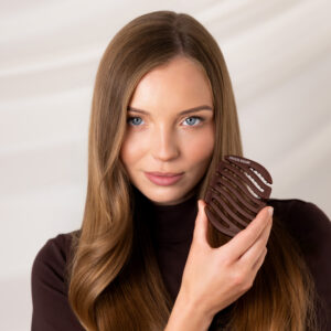 Modelka patrząca w obiektyw i prezentująca przy twarzy ciemnobrązową szczotkę Sister Young MILA Chocolate Coffee.