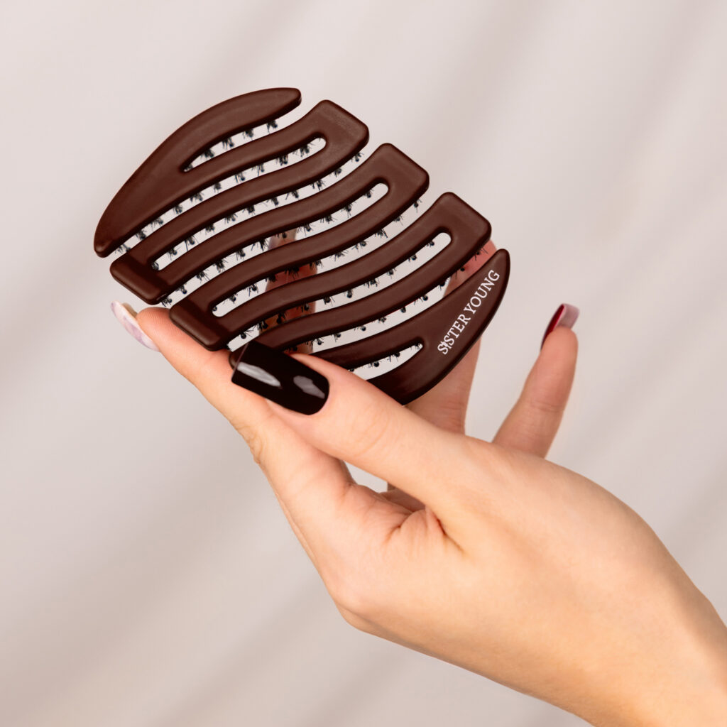 Ciemnobrązowa szczotka Sister Young MILA Chocolate Coffee na otwartej dłoni, widok tylnej części korpusu.