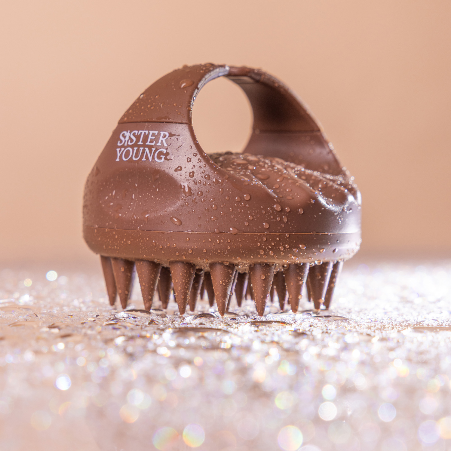 Zbliżenie szczotki Sister Young AURA Chocolate Coffee z zaokrąglonym uchwytem, wypustkami masującymi i kroplami wody.